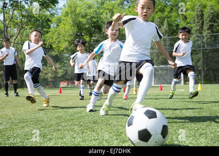 Der Trainer mit den Jungs Fußball spielen in dem Fußballplatz Stockfoto