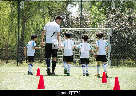 Der Fußball-Trainer nahm den jungen zu Fuß in das Fußballfeld Stockfoto