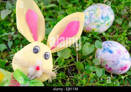 Easter Bunny Puppe und ein Wasser gefärbt Ei auf der Wiese liegend Stockfoto