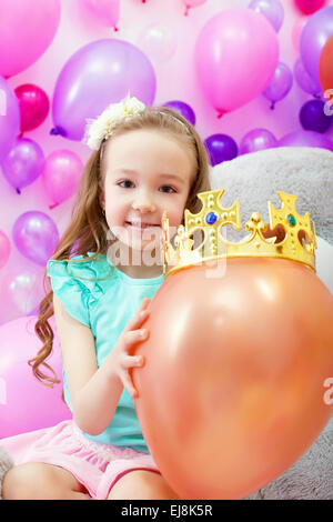 Fröhliches Mädchen spielerisch Ballon Krone aufsetzen Stockfoto