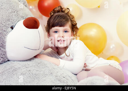 Entzückende Mädchen posiert auf Teddybär liegend Stockfoto