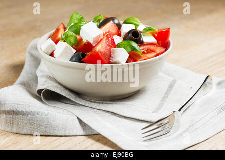 Griechischer Salat in Schüssel auf Holztisch Stockfoto