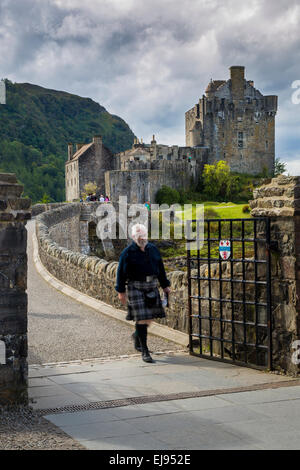 Mann in einem Kilt geht über die Brücke von Eilean Donan Castle, Highlands, Schottland, UK Stockfoto