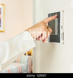 Kaukasische Dame drängenden modernen thermostat Stockfoto