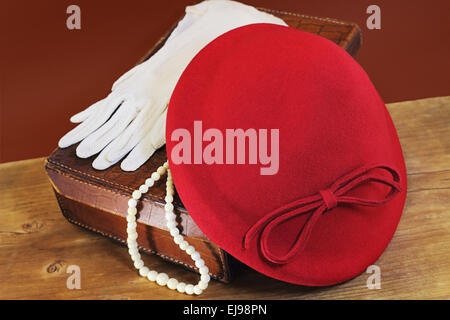 Red Hat, weiße Handschuhe und Knochen Perlen auf Ledertasche Stockfoto