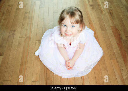 Eine schöne kleine Mädchen sitzen auf dem Boden mit einem Kleid Stockfoto