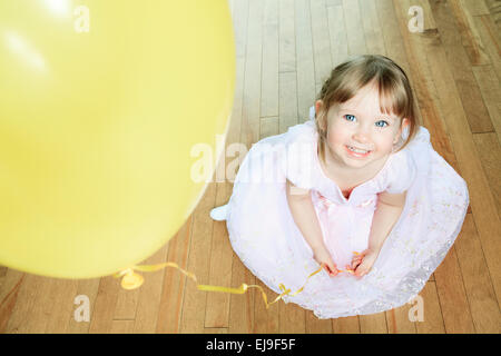 Ein nettes kleines Mädchen sitzen auf dem Boden mit einem Ballon Stockfoto