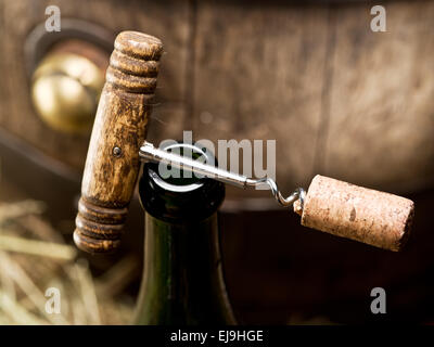 Öffnen einer Weinflasche mit Korkenzieher mit Holzfass auf dem Hintergrund. Stockfoto