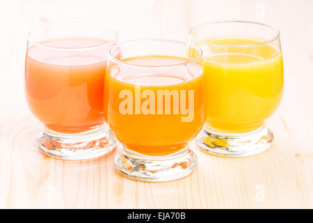 Drei Gläser von frischen Säften. Grapefruit, Orange und Apfel und Karotte Saft auf hölzernen Hintergrund. Stockfoto