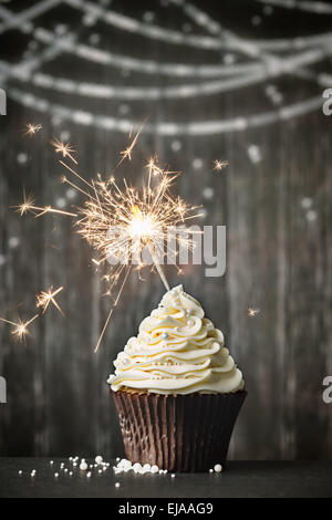 Cupcake mit Wunderkerze auf einem hölzernen Hintergrund Stockfoto