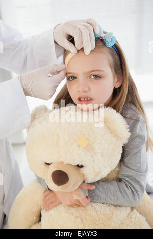 Mädchen bekommen ein Pflaster auf der Stirn Stockfoto