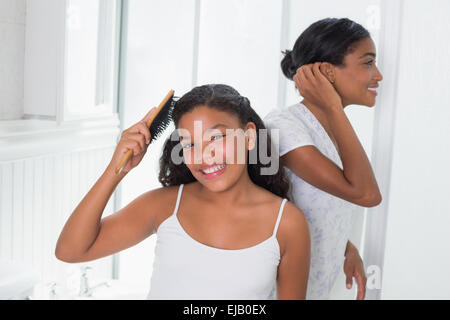 Niedliche Tochter Bürsten Haare mit ihrer Mutter Stockfoto