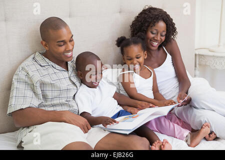 Glückliche Familie auf Bett Buch Stockfoto