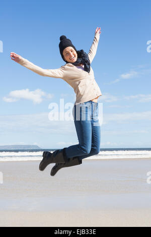 Hübsche Blondine in Jeans sprang am Strand Stockfoto