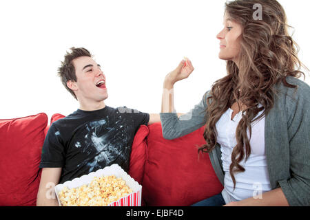 Porträt des jungen Paares sitzen zusammen auf dem Sofa zu Hause vor dem Fernseher, freudig lächelnd essen Popcorn genießen Sie eine Nacht in zusammen zu schließen. Home Lifestyle und Entertainment-Technologie. Stockfoto