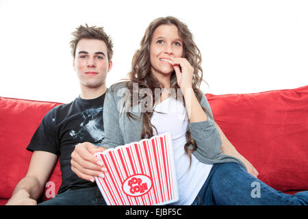 Porträt des jungen Paares sitzen zusammen auf dem Sofa zu Hause vor dem Fernseher, freudig lächelnd essen Popcorn genießen Sie eine Nacht in zusammen zu schließen. Home Lifestyle und Entertainment-Technologie. Stockfoto