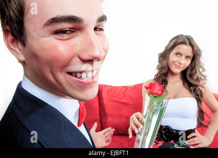 Man bietet eine Rose zu seiner Freundin in ihrem Wohnzimmer Stockfoto