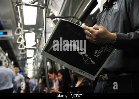 Singapur. 24. März 2015. Ein Mann liest eine Zeitung mit einem Foto von Singapurs ehemaliger Premierminister Lee Kuan Yew auf der Titelseite auf eine u-Bahn in Singapur, 24. März 2015. Lee Kuan Yew, ehemaliger Premierminister von Singapur, starb am 03:18 am Montag im Alter von 91, laut Aussage von the Prime Minister es Office (PMO) am Montag veröffentlicht. Bildnachweis: Dann Chih Wey/Xinhua/Alamy Live News Stockfoto