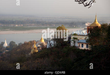 Blick auf goldene buddhistische Tempel, die im Sonnenuntergang auf dem Sagaing-Hügel über dem Fluss Ayeyarwady in der Nähe des Mandalay Myanmar (Birma) glühen Stockfoto