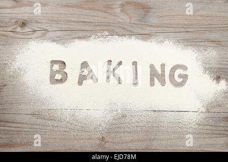 Das Wort Backen in weißem Mehl auf einem alten Holztisch, niedrigen hellen Vintage Ton geschrieben. Stockfoto