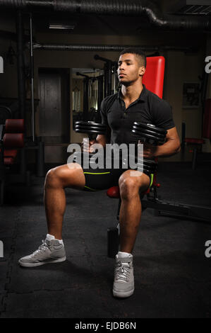 junger Mann sitzen auf Bank in Turnhalle Stockfoto