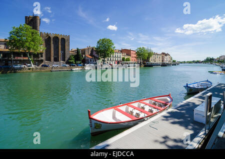 Ein kleines Boot festgemacht am Fluss Hérault übersehen von Agde Kathedrale in der Stadt Agde, Herault, Languedoc-Roussillon, Frankreich Stockfoto