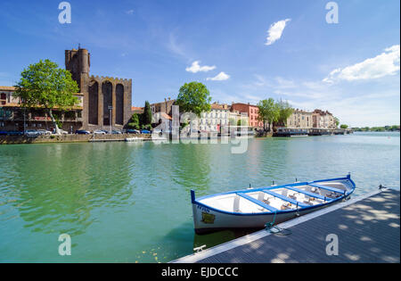 Ein kleines Boot festgemacht am Fluss Hérault übersehen von Agde Kathedrale in der Stadt Agde, Herault, Languedoc-Roussillon, Frankreich Stockfoto