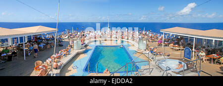 Panoramablick auf Passagiere entspannen in der Sonne am Pool auf Kreuzfahrtschiff auf hoher See Stockfoto