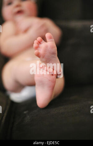 Ein Baby auf einem Sofa liegend eine Windel zu tragen. Stockfoto