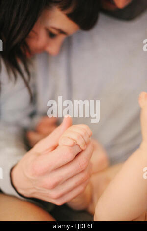 Des Vaters Hand umklammert ein junges Baby kleine Hand in seiner. Stockfoto