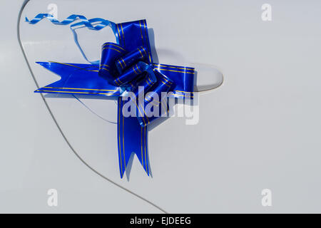 Ein gebundener blaues Band macht eine Hochzeitsdekoration auf einem weißen Auto Türgriff Stockfoto