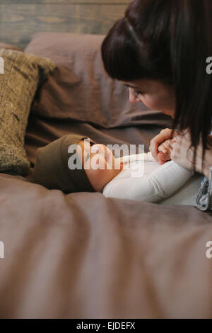 Eine Mutter und ihr junges Baby spielen auf einem Bett. Stockfoto