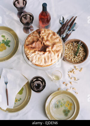 Ein Tisch gedeckt mit Gerichten von Essen, Nüssen, Kuchen und eine Flasche Wein. Stockfoto