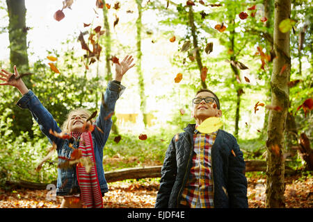 Ein Mädchen und ihr Bruder Herbstlaub in die Luft zu werfen. Stockfoto