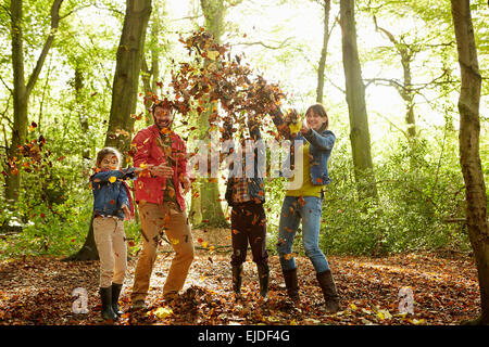 Eine Familie werfen getrocknete Blätter in die Luft in den Wäldern im Herbst. Stockfoto