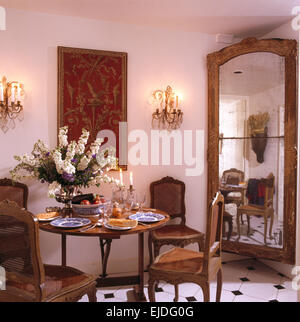 Großer antiker Spiegel in Ecke des Stadthaus Esszimmer mit antiker Tisch und hinteren Rohrstühlen Stockfoto