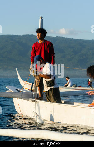 Lovina, Bali, Indonesien. Ein einheimischer Fischer arbeitet daran, um einen Hai zu landen. Stockfoto