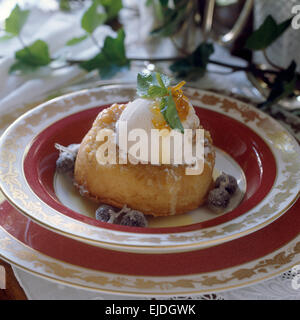 Nahaufnahme von einem rum Baba mit Rum und Rosinen-Eis in einem China-Teller Stockfoto