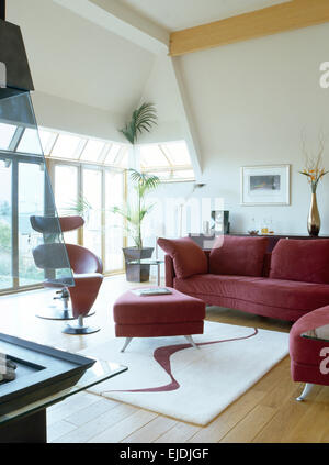 Tief rosa Sofa und Ottomane in modernen offenen Wohnraum mit abstrakten gemusterten Teppich Stockfoto