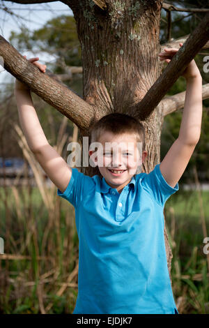 Kleiner Junge stützte sich auf Eiche im Park, Porträt Stockfoto