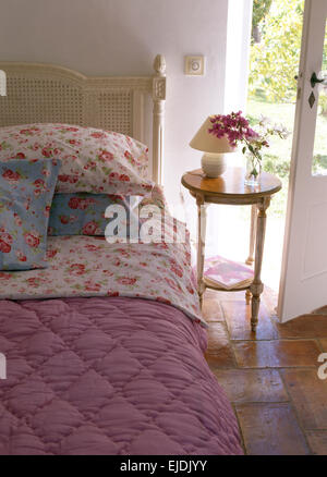 Rose gemusterte Kissen und rosa Quilt in französischer Landhaus Schlafzimmer mit kleinen Nachttisch Stockfoto