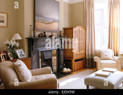 Großes Bild oben schwarz Kamin im Wohnzimmer Stadthaus mit cremefarbenen Sessel und Ottomane Hocker Stockfoto