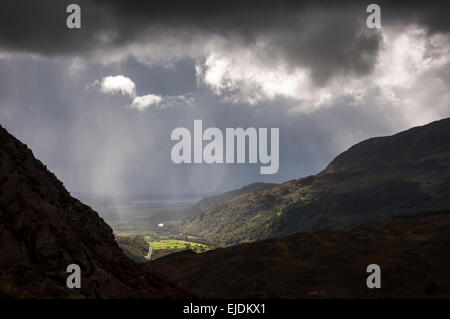 Dramatische Beleuchtung in der Nähe von Bedggelert in Snowdonia, Nordwales. Sonnenstrahlen brechen durch die niedrige Wolke. Stockfoto