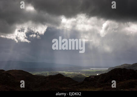 Dramatische Beleuchtung in der Nähe von Bedggelert in Snowdonia, Nordwales. Sonnenstrahlen brechen durch die niedrige Wolke. Stockfoto