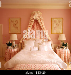 Coronet und Vorhänge über Bett mit weißen Decke und Kissen in rosa neunziger Jahre Schlafzimmer entworfen von Henrietta Spencer-Churchill Stockfoto