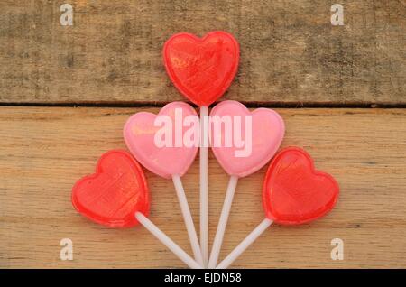 Herzförmige Lollis auf Palette holz Hintergrund angezeigt. Festive Fun Design zu Feiertage oder Geburtstage, Romantik, Valentinstag feiern. Stockfoto