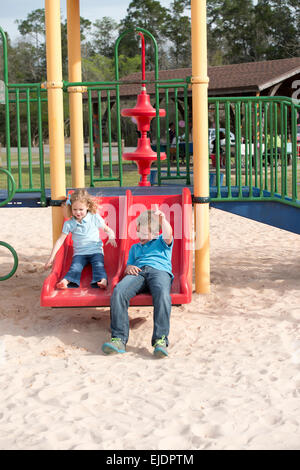 Jungen und Mädchen gehen Rutsche im Park Spielplatz Stockfoto