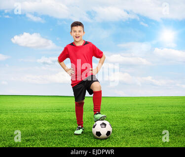 In voller Länge Portrait von fröhlicher Jugendlicher an einem sonnigen Sommertag über einen Fußball auf der grünen Wiese stehen. Schuss mit Neigung und Stockfoto