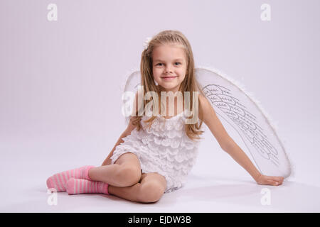 Sechs Jahre altes Mädchen in einen strahlenden Engel Kostüm mit Flügeln auf weißem Hintergrund Stockfoto