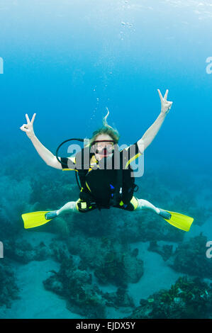 Ein weiblicher Taucher posiert für die Kamera mit Peace-Zeichen, St. Lucia. Stockfoto